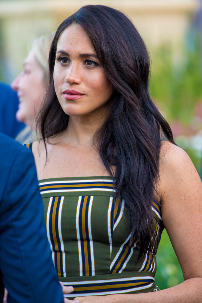 Meghan Markle frowning wearing a striped green dress
