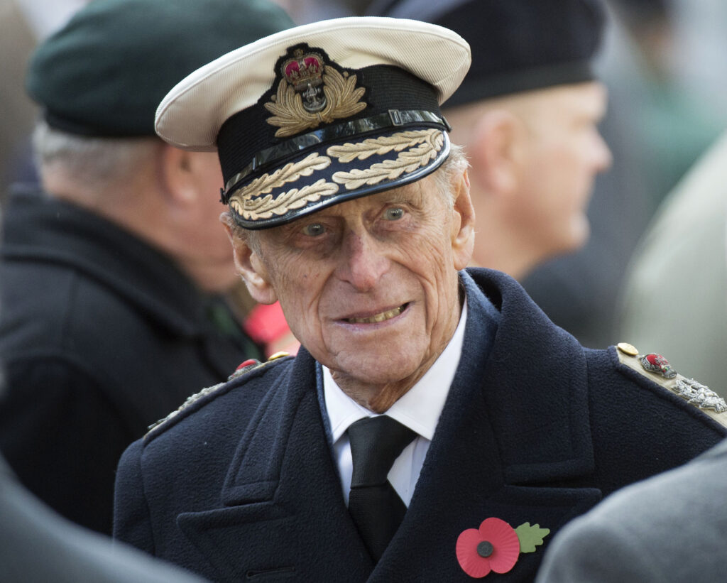 Prince Philip wears a coat with a red poppy