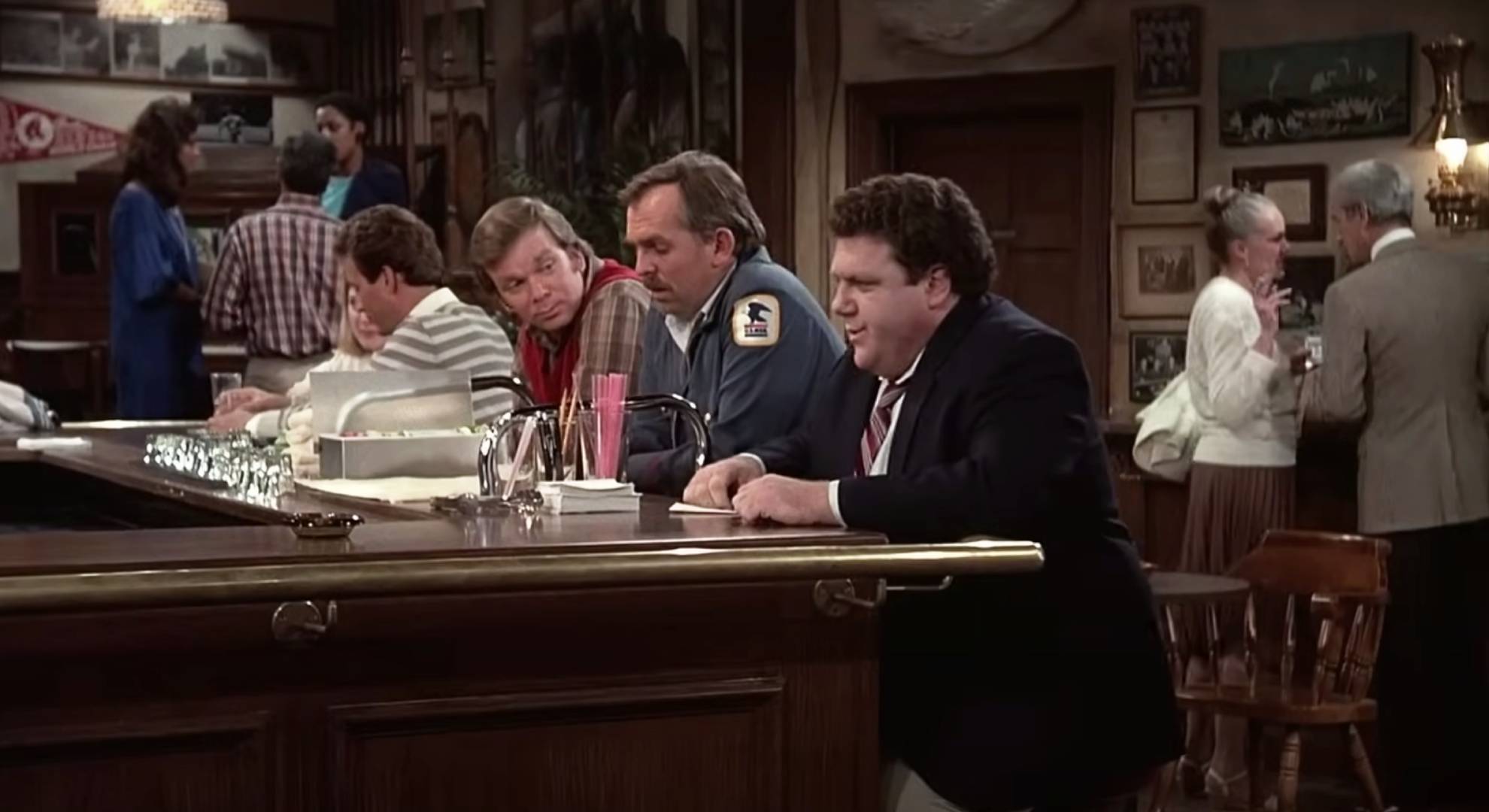George Wendt sits at the bar in character as Norm in Cheers