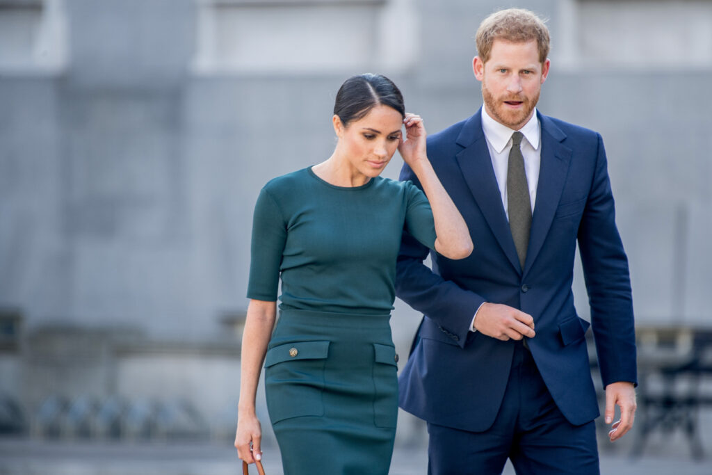 Meghan Markle facing down and Prince Harry in suit 