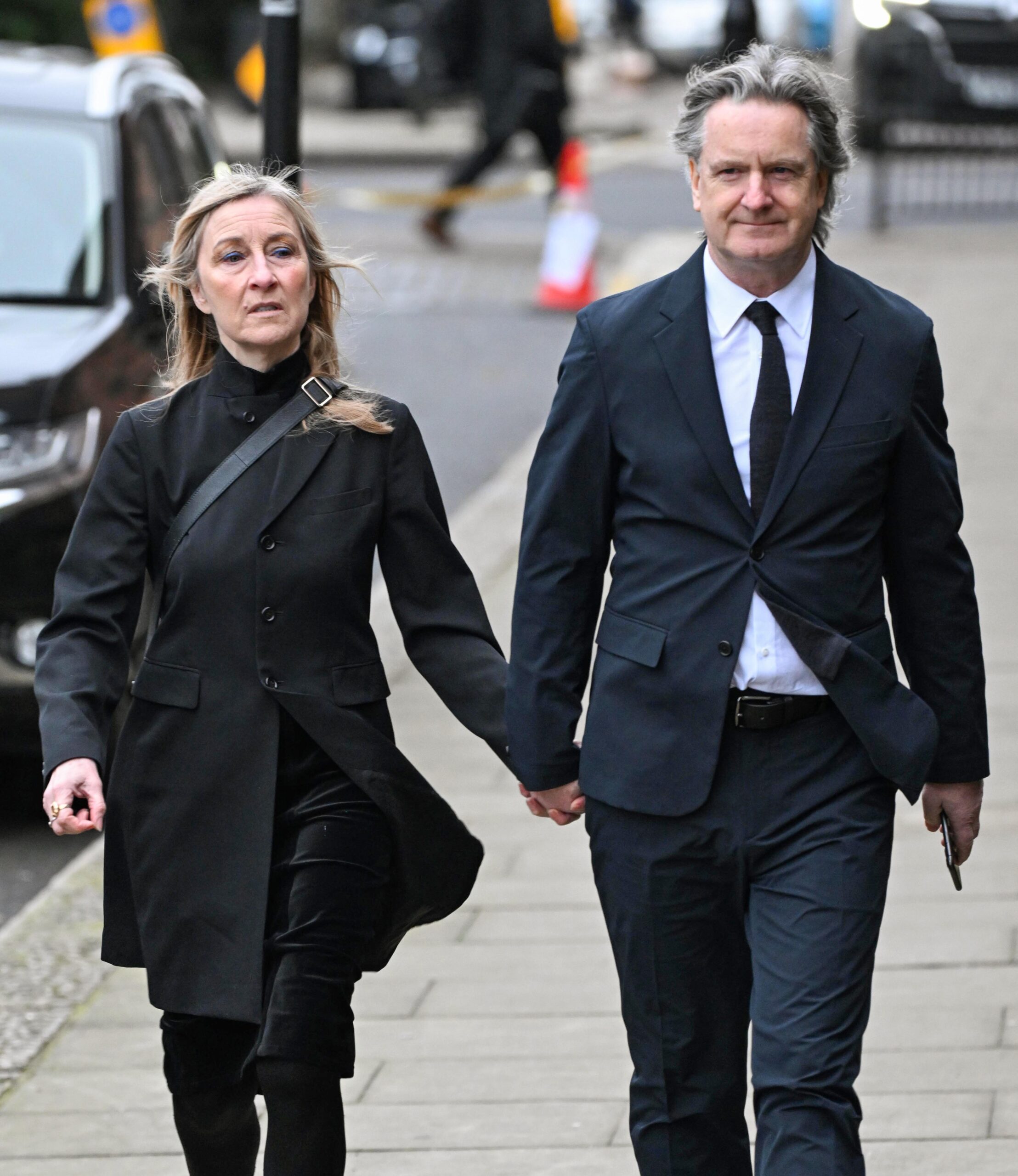 Fiona Phillips and Martin Frizell wearing black coats holding hands
