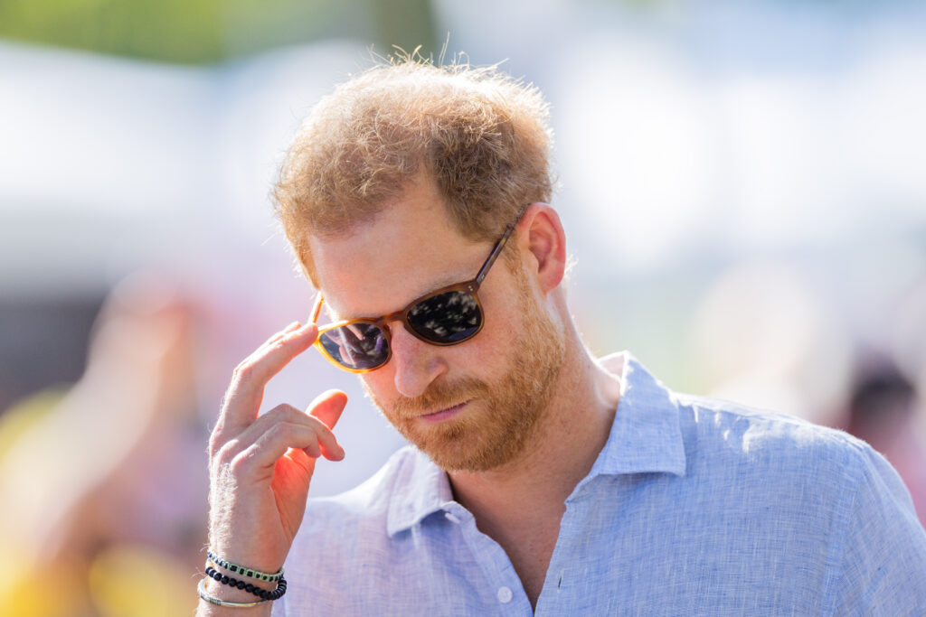 Prince Harry wears sunglasses and a blue shirt