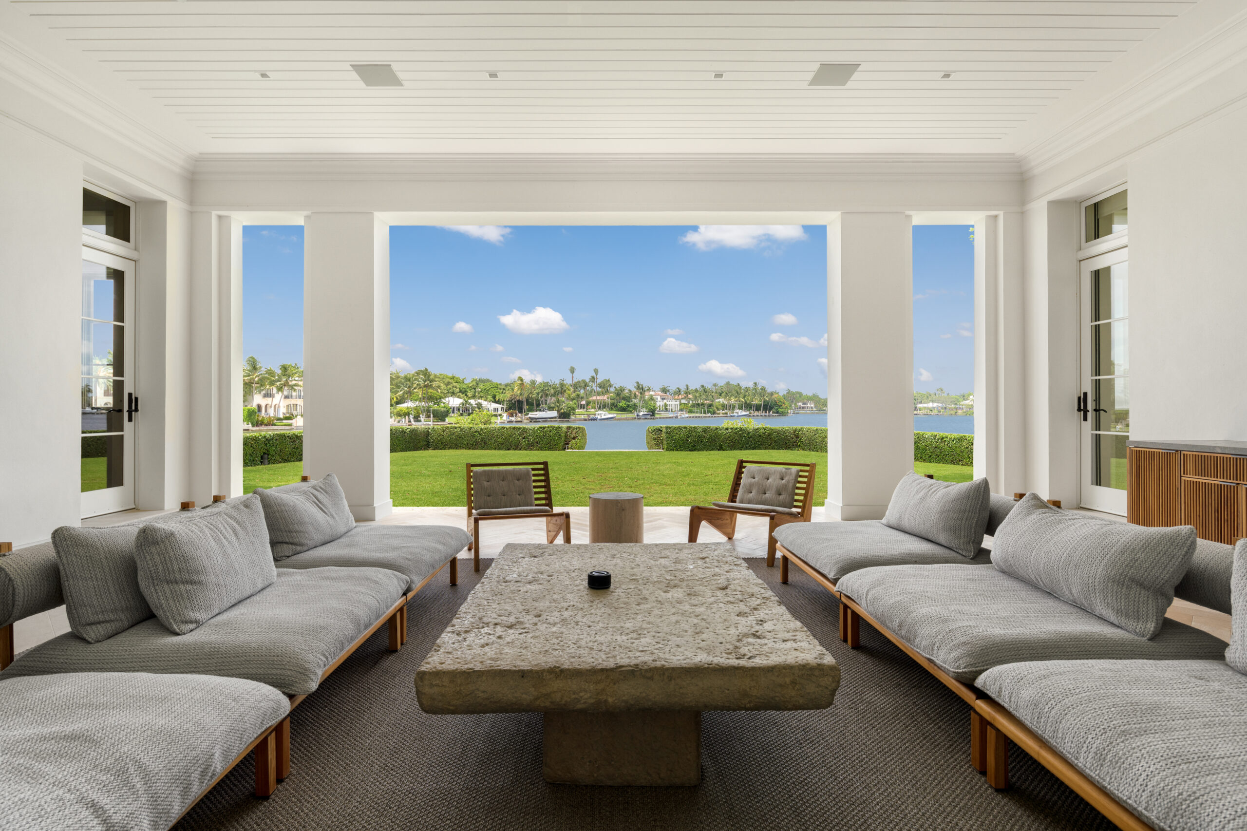 Robbie Williams' living area featuring a table, grey couches, and a giant window.