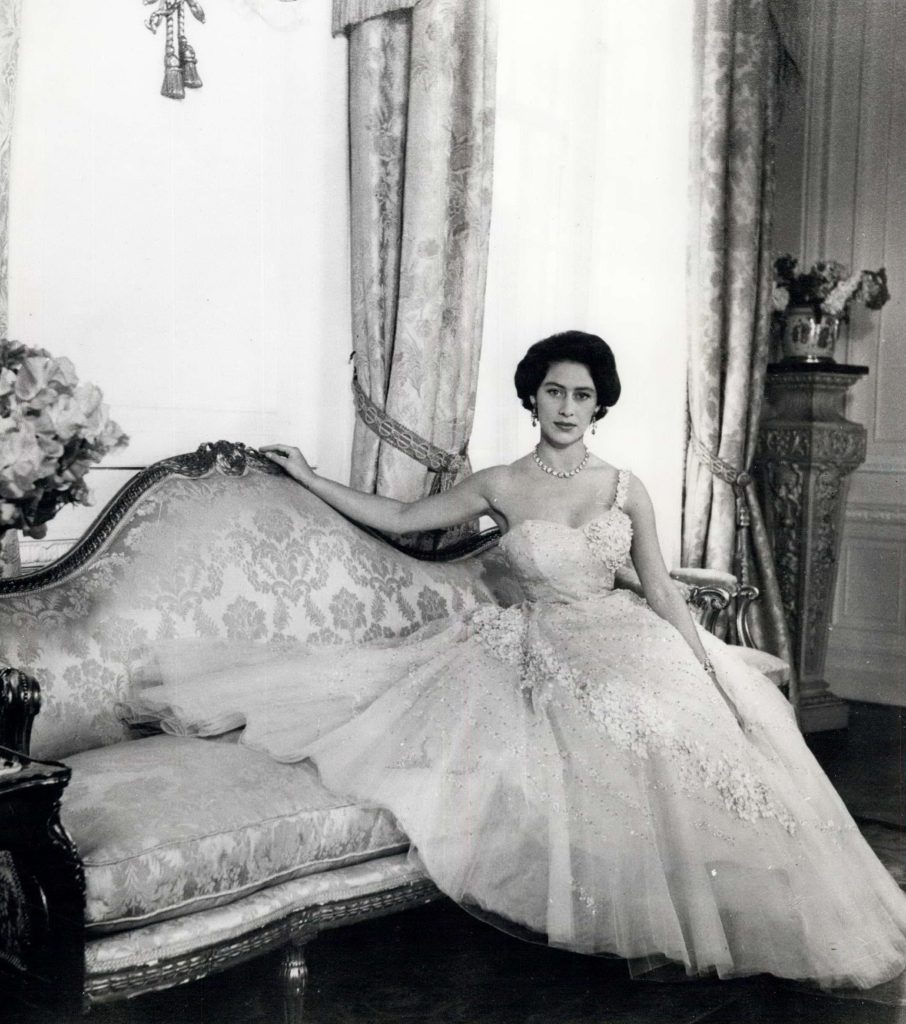 1956 - Princess Margaret photographed by Cecil Beaton in the Drawing Room of Clarence House, her London residence. The photo was made in connection with Princess Margaret on her 26th birthday on August 21. Her Royal Highness wears an evening dress of pink tulle embroidered with flowers and sequins. Her hair is worn short, softly waved, and piled high on her head. She is lounging on a sofa.