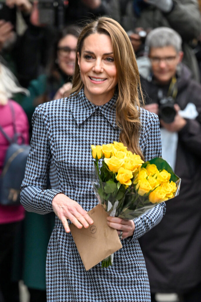 Kate Middleton walking and smiling with flowers