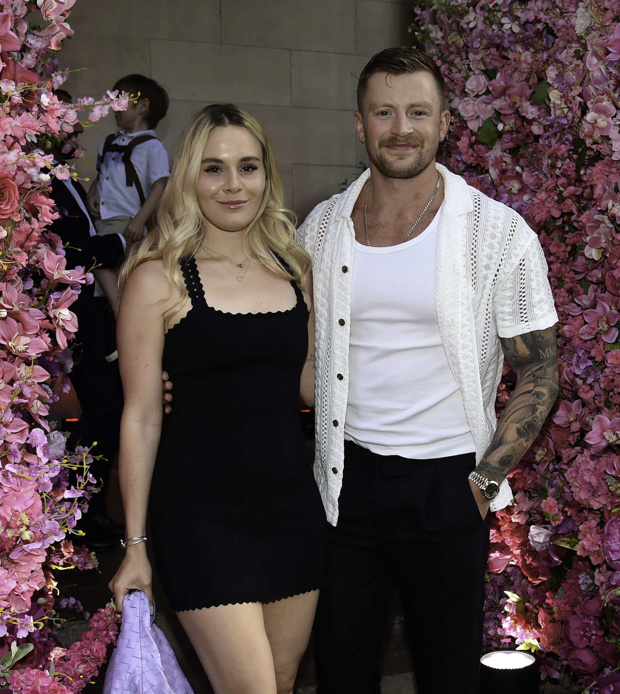 Holly Ramsay and Adam Peaty beside some pink flowers