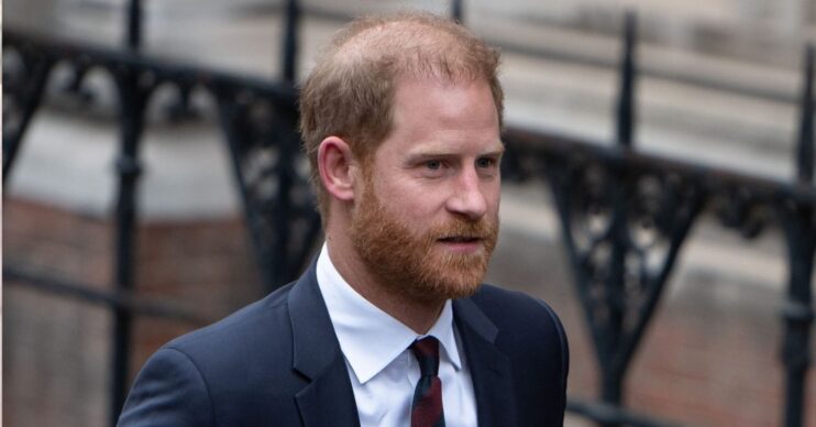 Prince Harry with a serious expression wearing a suit and tie