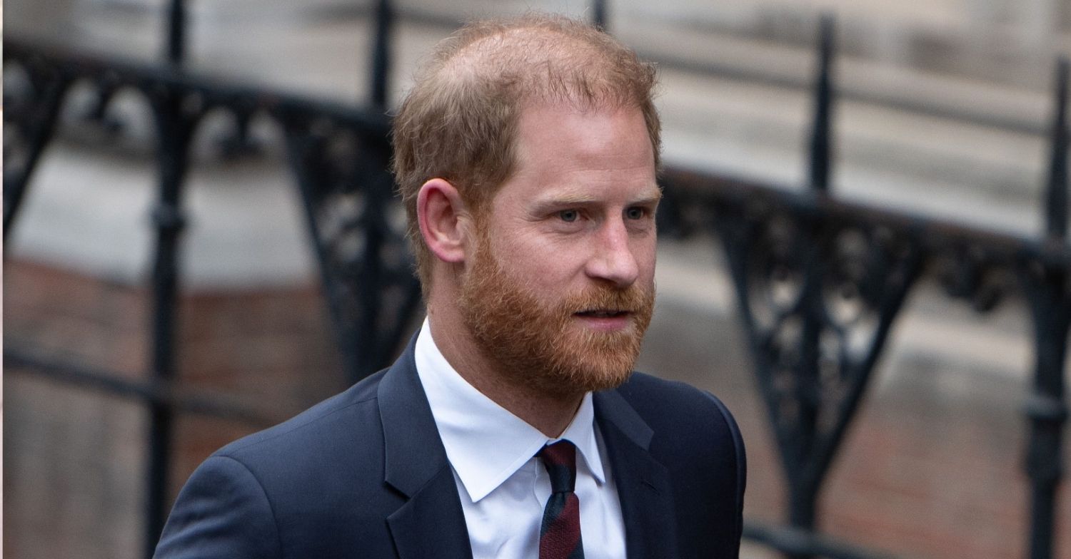 Prince Harry with a serious expression wearing a suit and tie