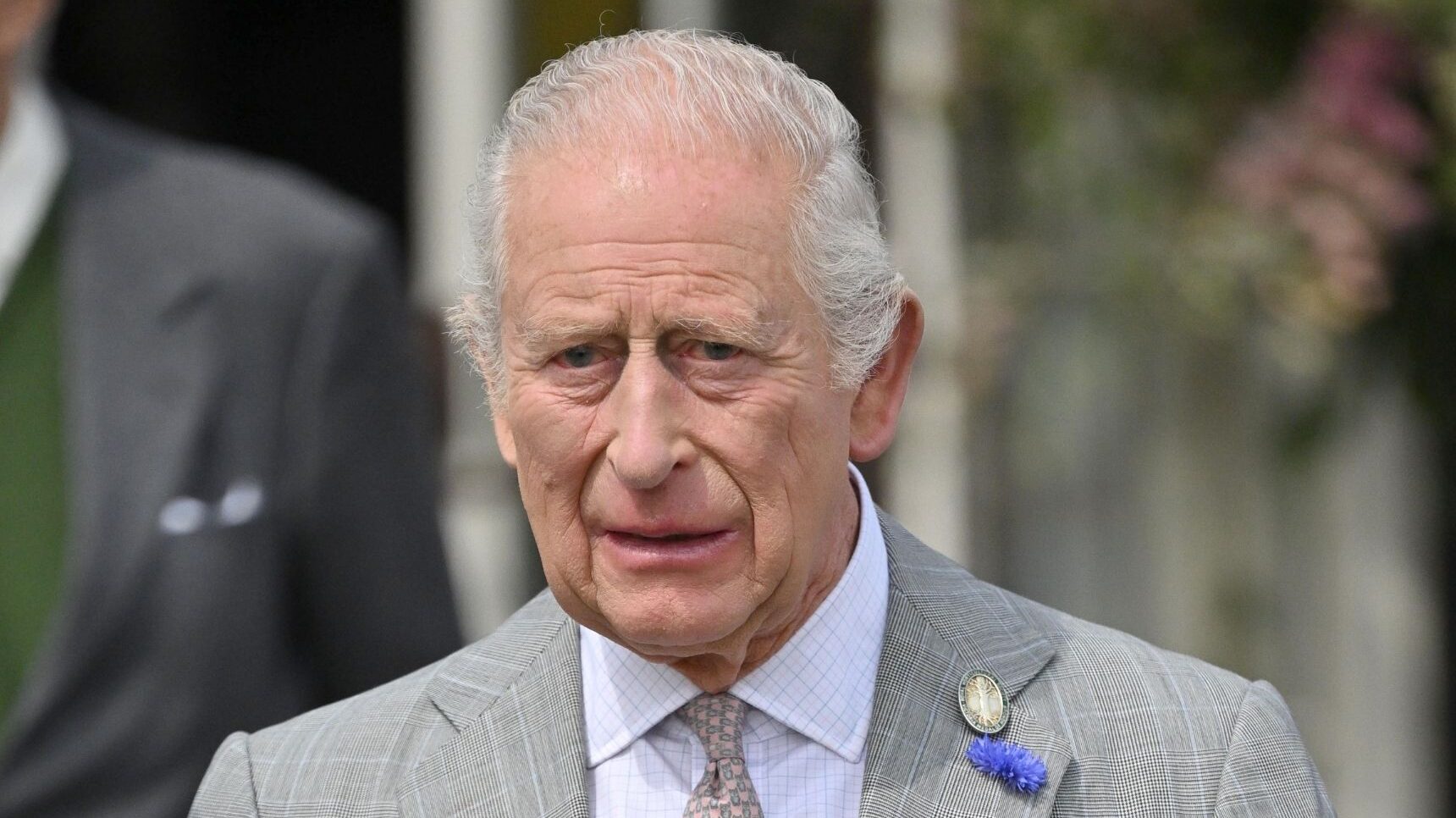 King Charles in grey suit looking worried