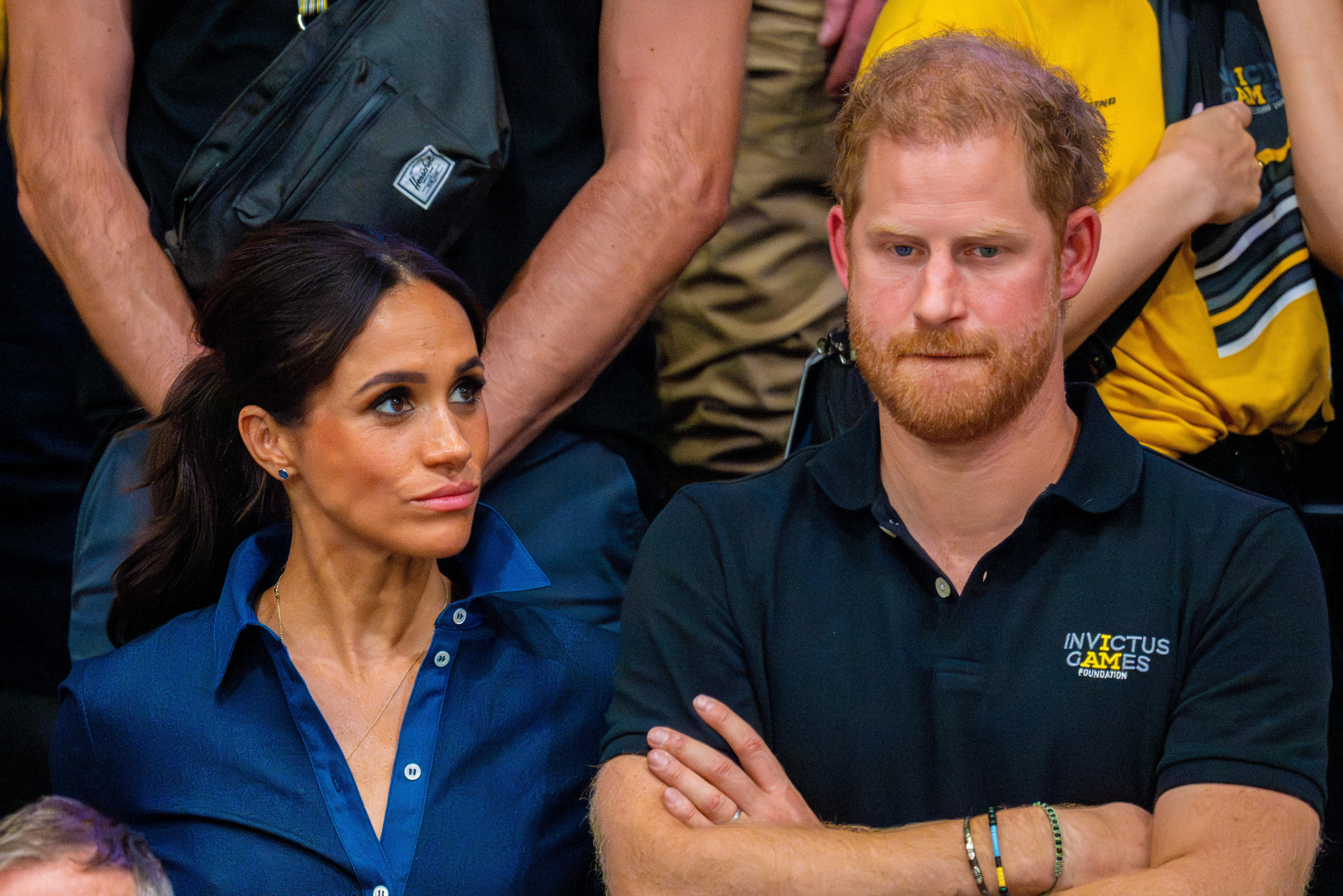 Meghan Markle scowling at a frowning Prince Harry