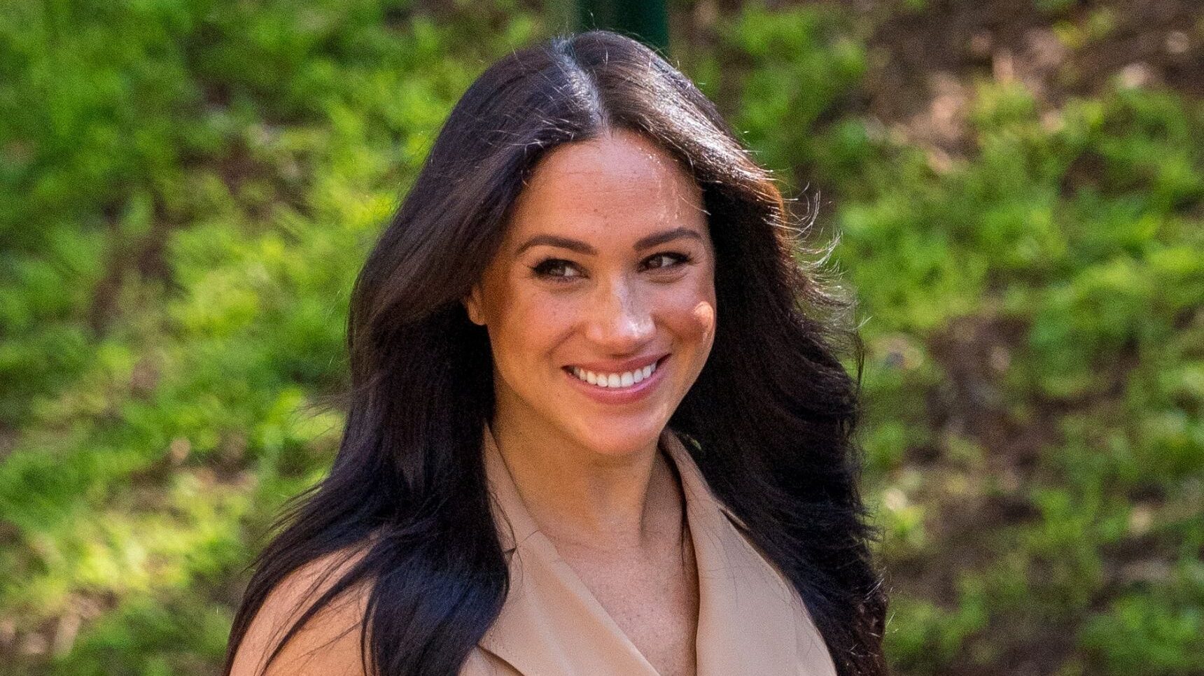 Meghan Markle smiling in beige dress