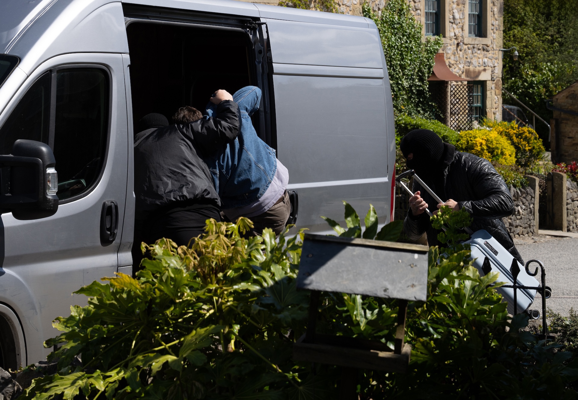 A man in a balaclava grabs Lewis and bundles him into the van