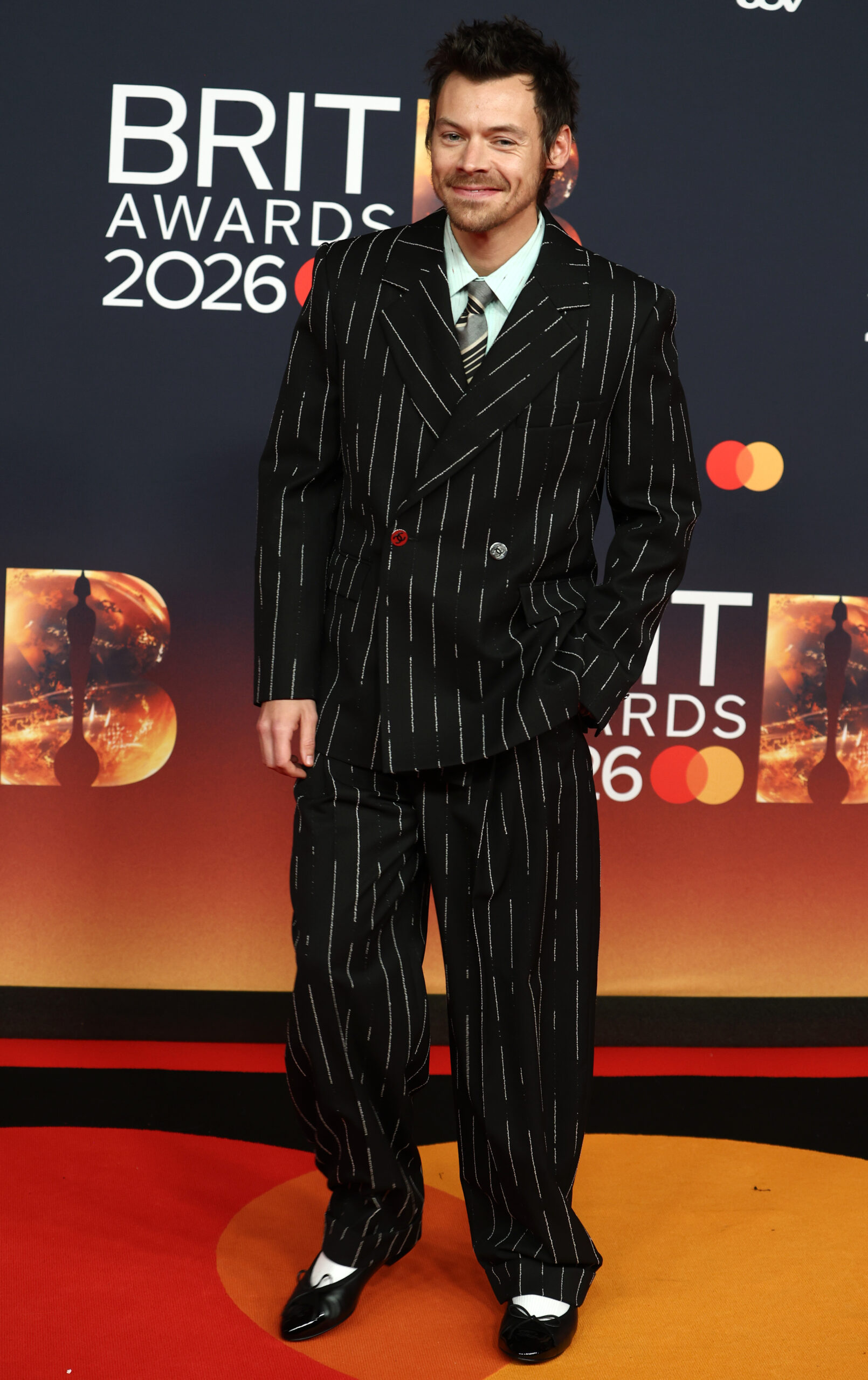 Harry Styles on the red carpet wearing a pinstripe suit at the Brit Awards 2026