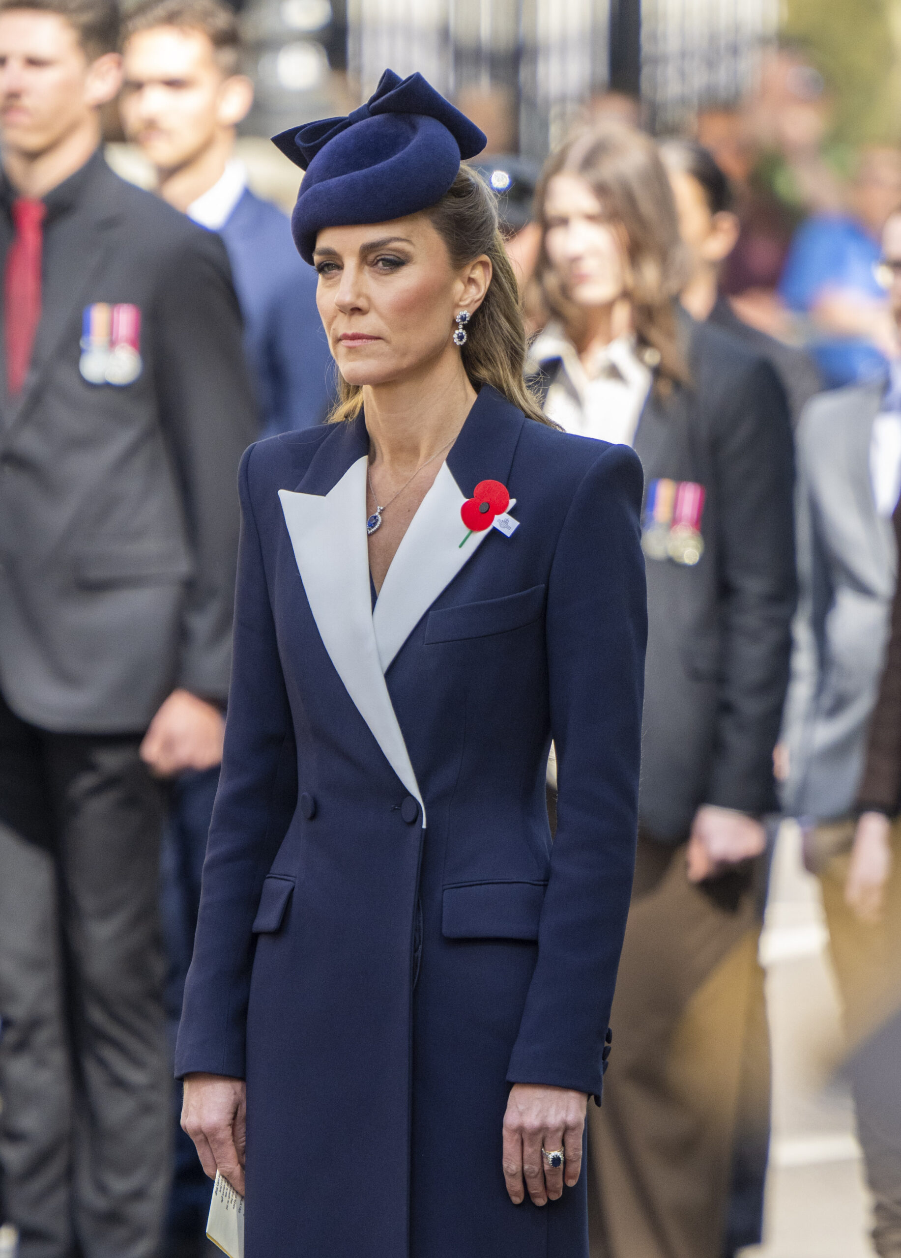 Princess Kate frowning, wearing a navy ensemble