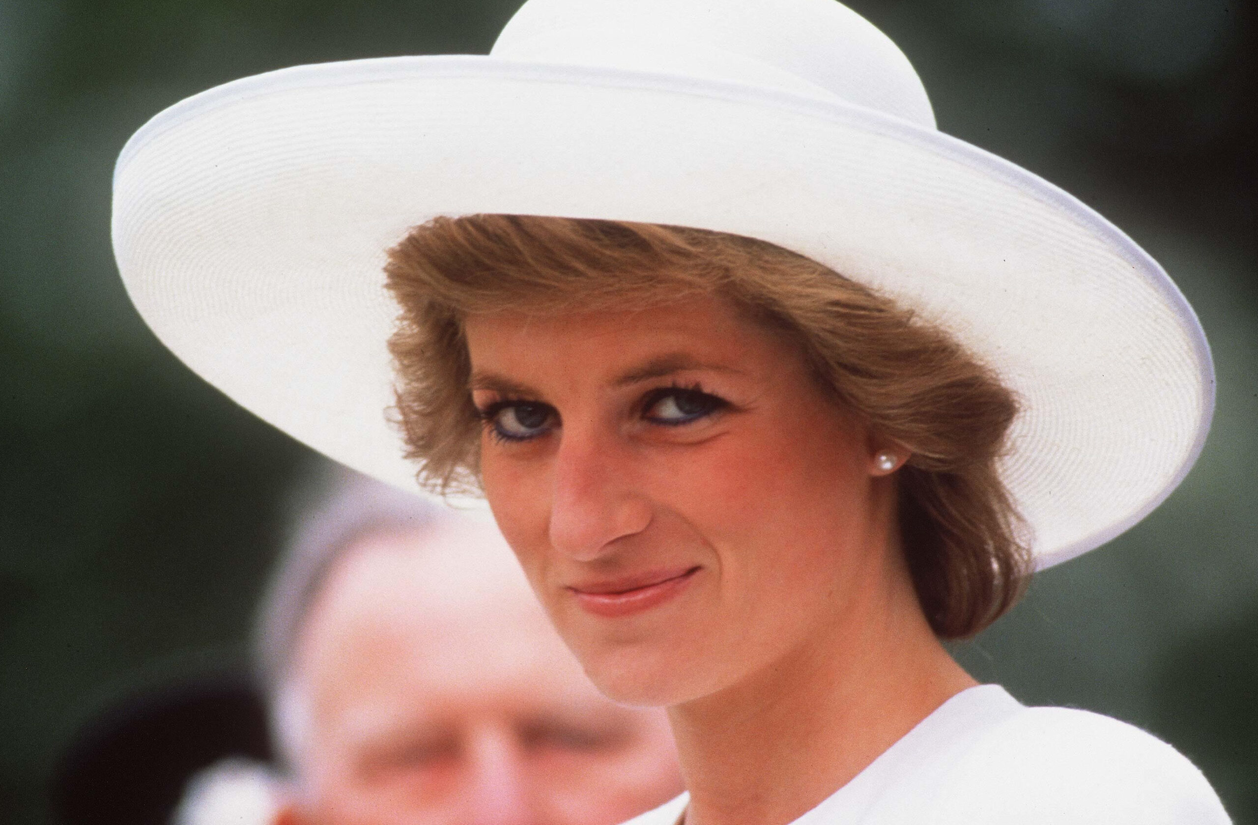 Princess Diana smiling. wearing a white hat