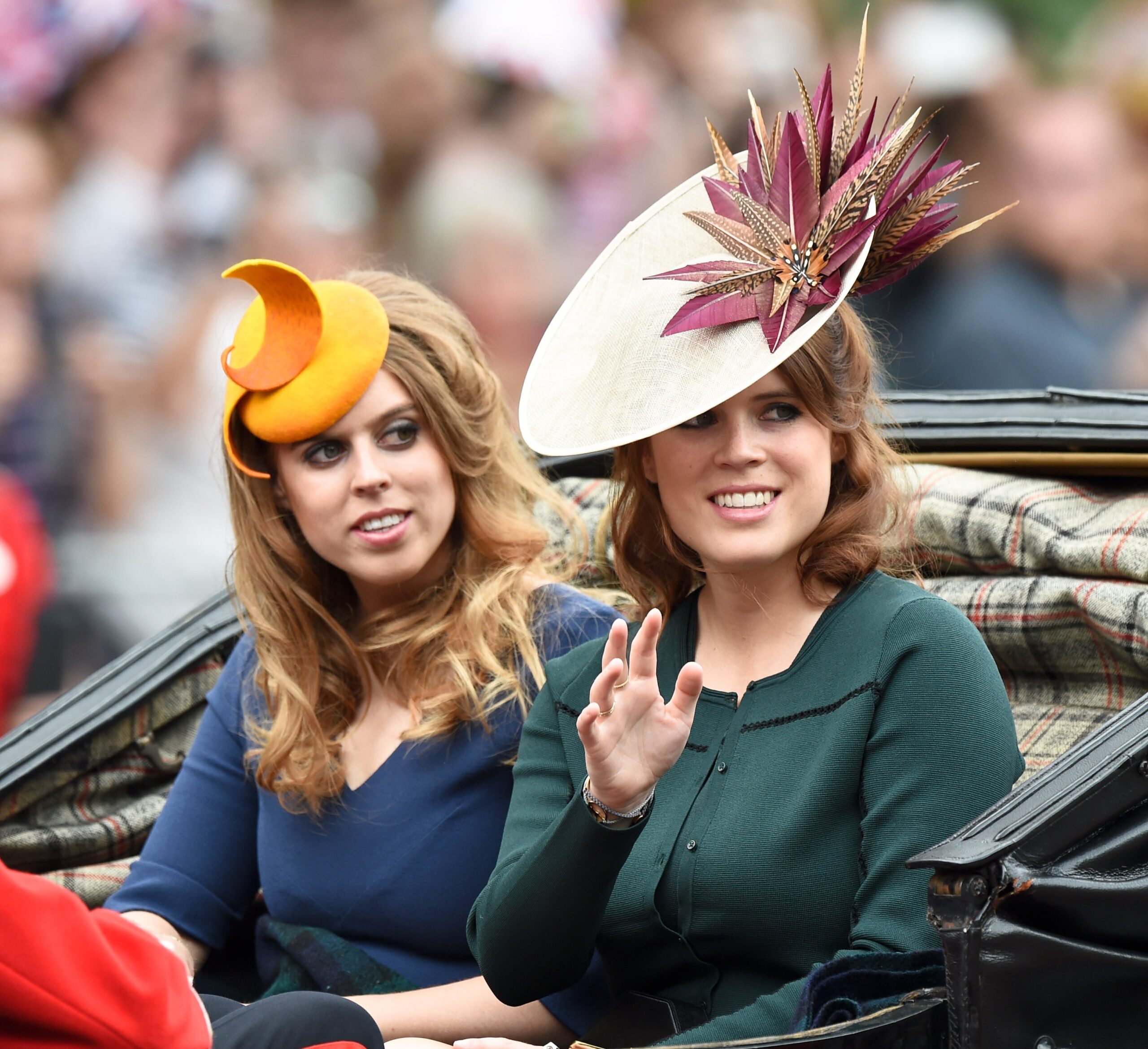 Princesses Beatrice and Eugenie riding in a carriage wearing hats