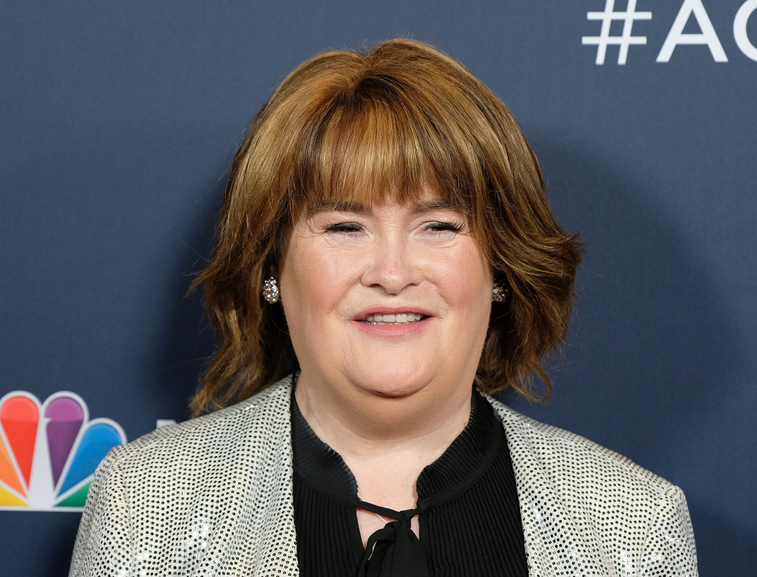 Susan Boyle smiling, flaunting a short brunette hairstyle