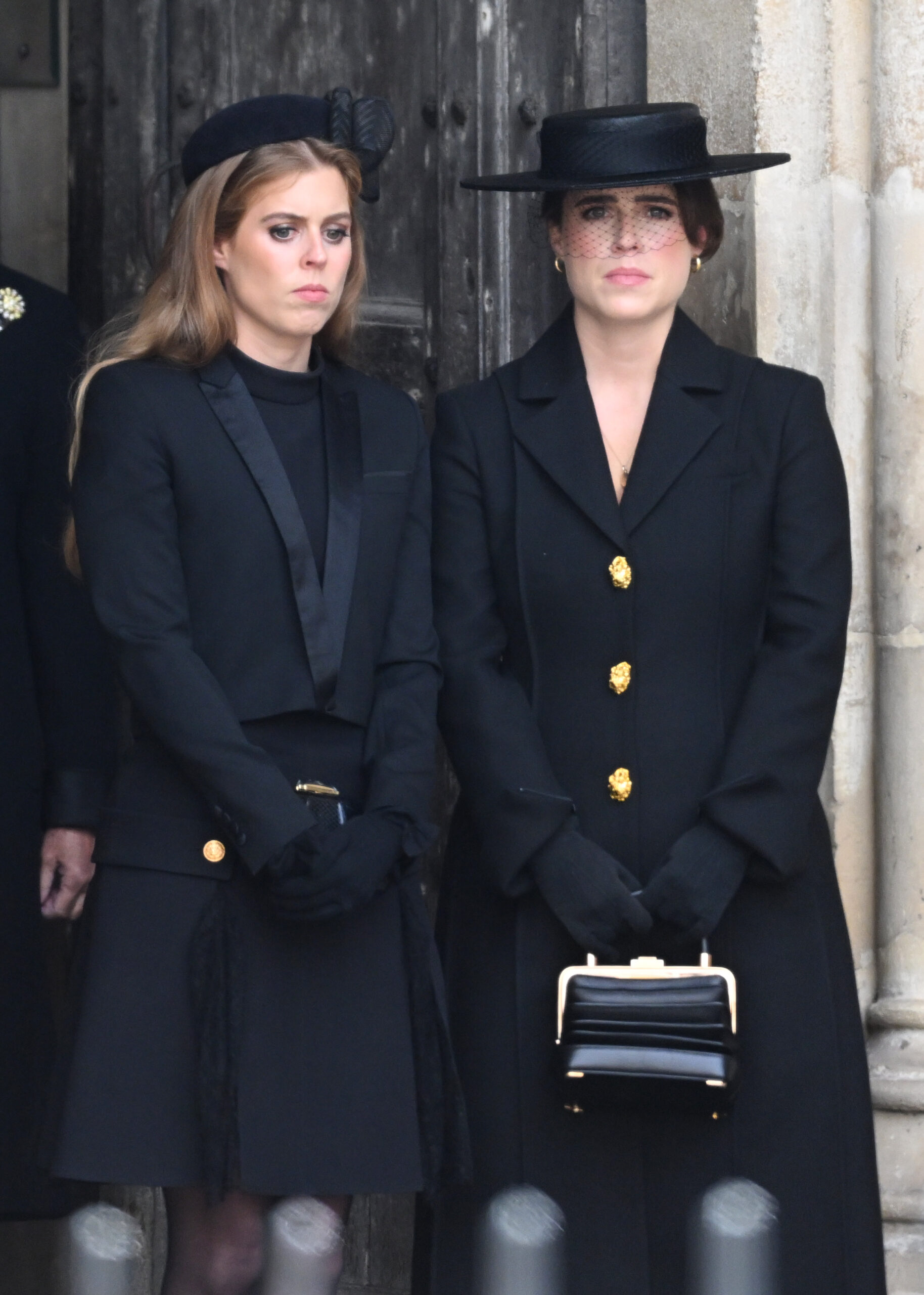 Princesses Beatrice and Eugenie frowning, both wearing black, photographed at The State Funeral Of Queen Elizabeth II