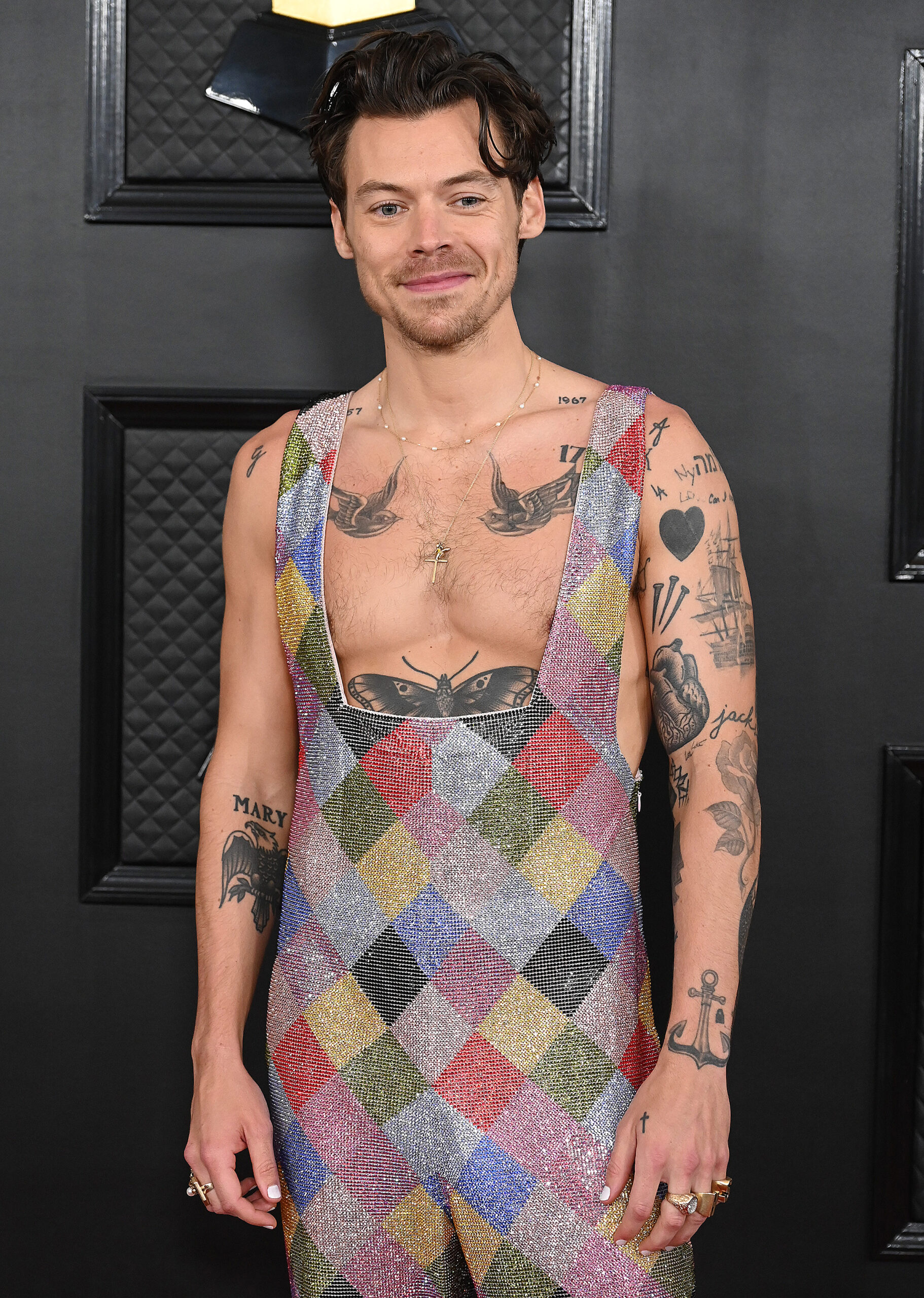 Harry Styles smiling wearing a sparkly jumpsuit
