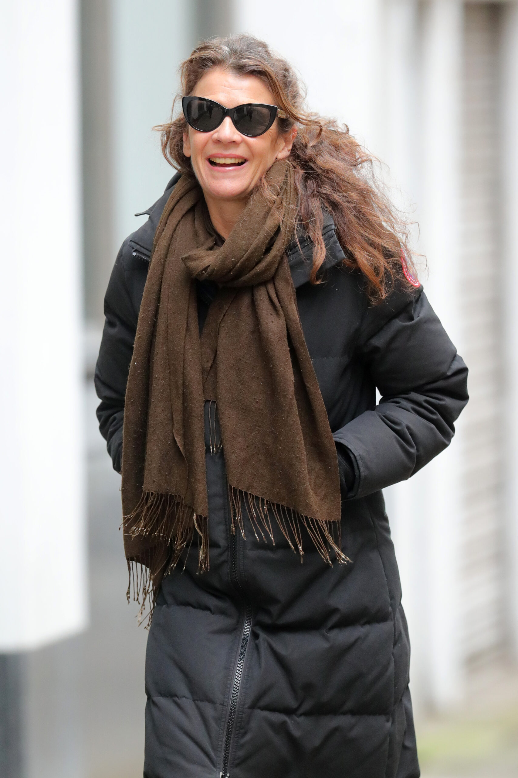 Annabel Croft smiling wearing a coat, scarf and sunglasses