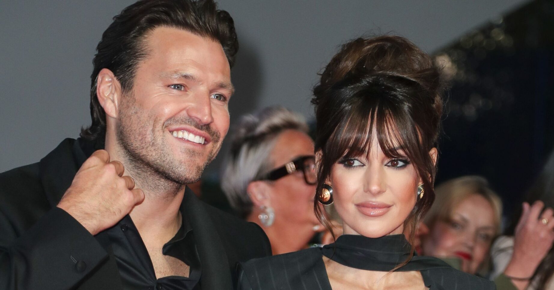 Mark Wright smiling beside Michelle keegan with a serious expression