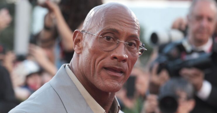 Dwayne Johnson with a serious expression wearing glasses