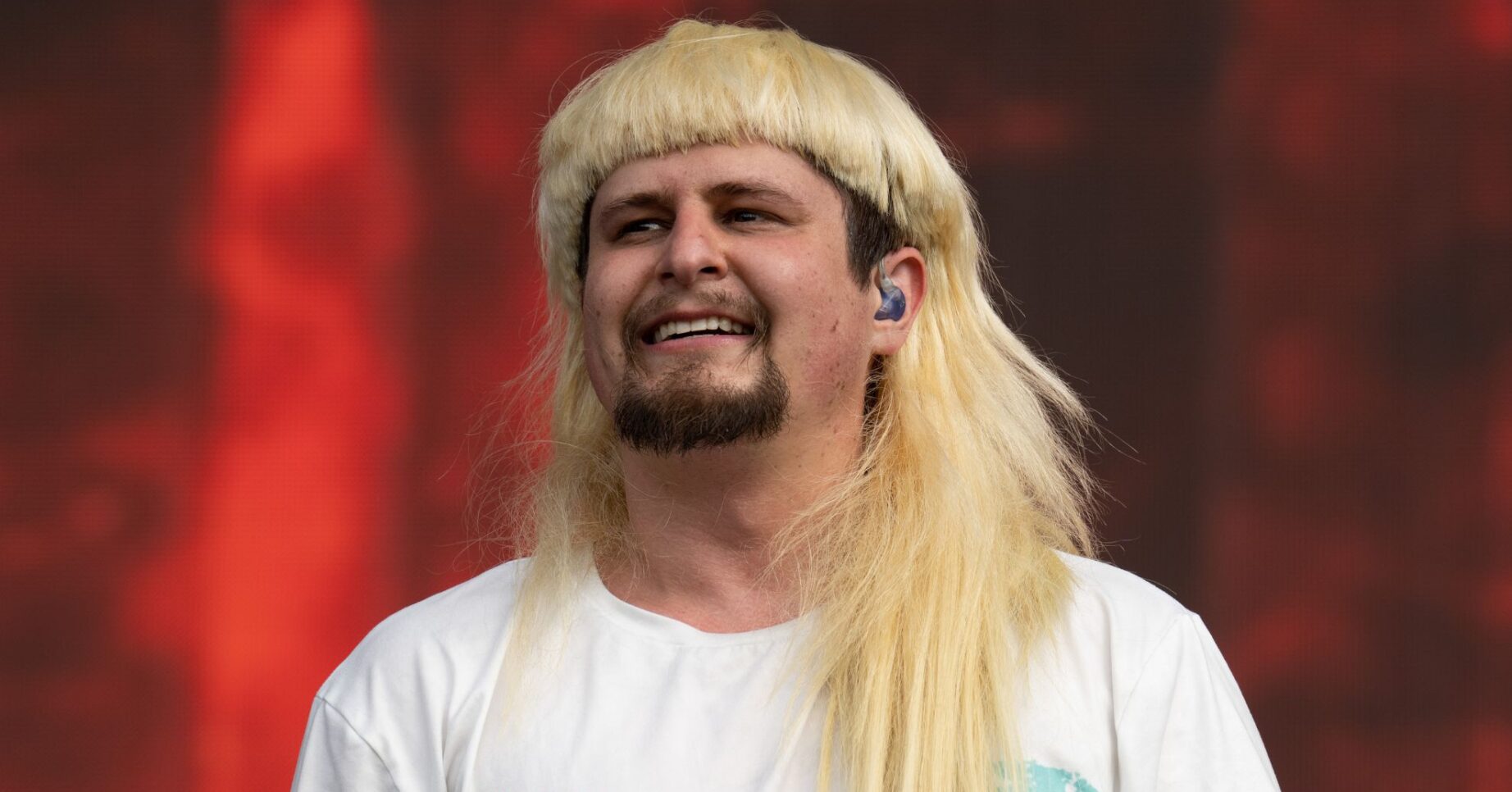 Oliver Tree with blonde hair smiling on stage