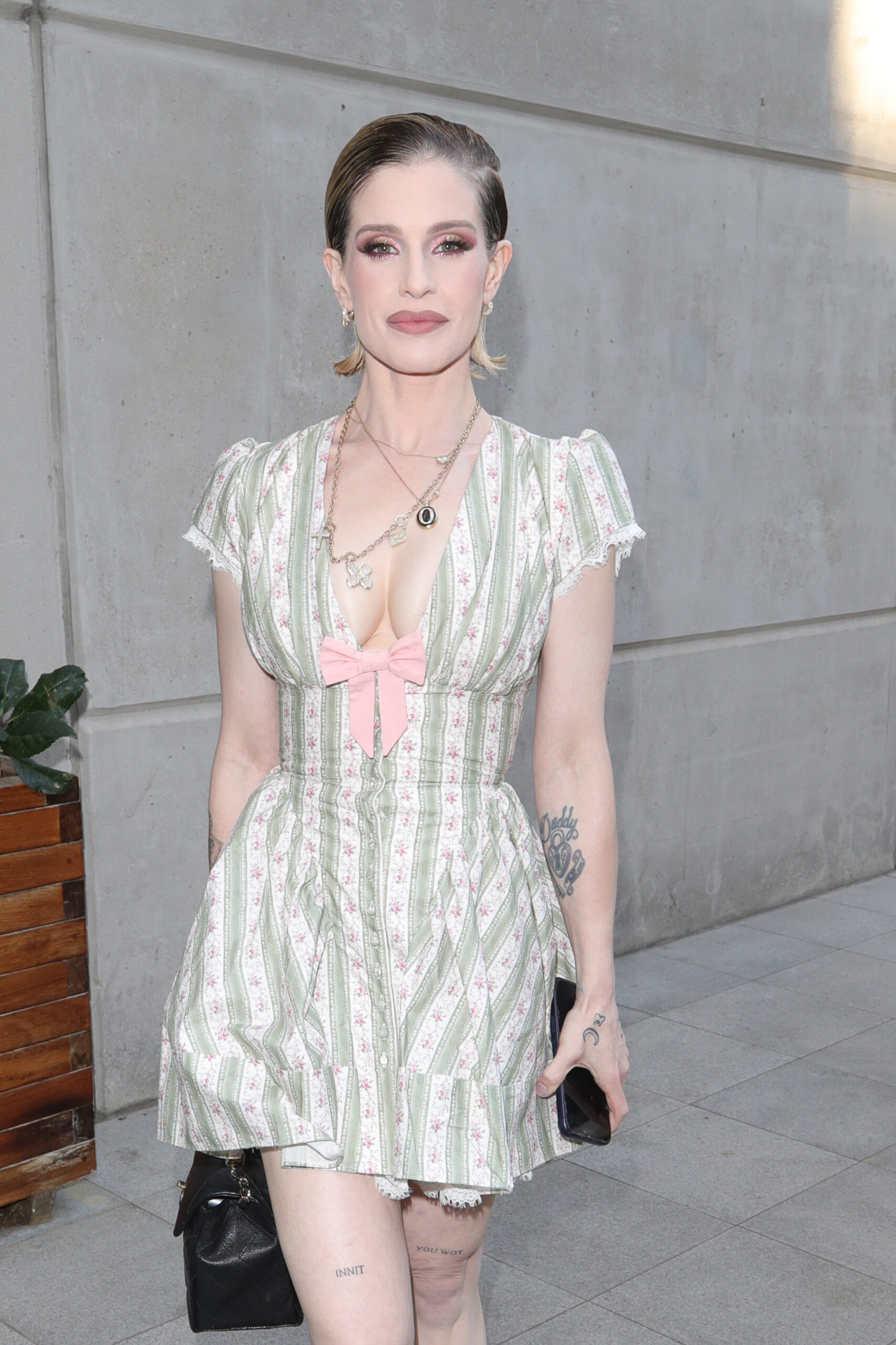 Kelly Osbourne wearing a green and cream dress with a pink bow