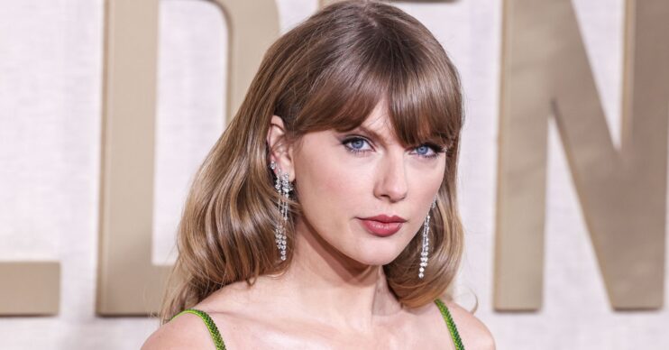 Taylor Swift frowning wearing a green dress