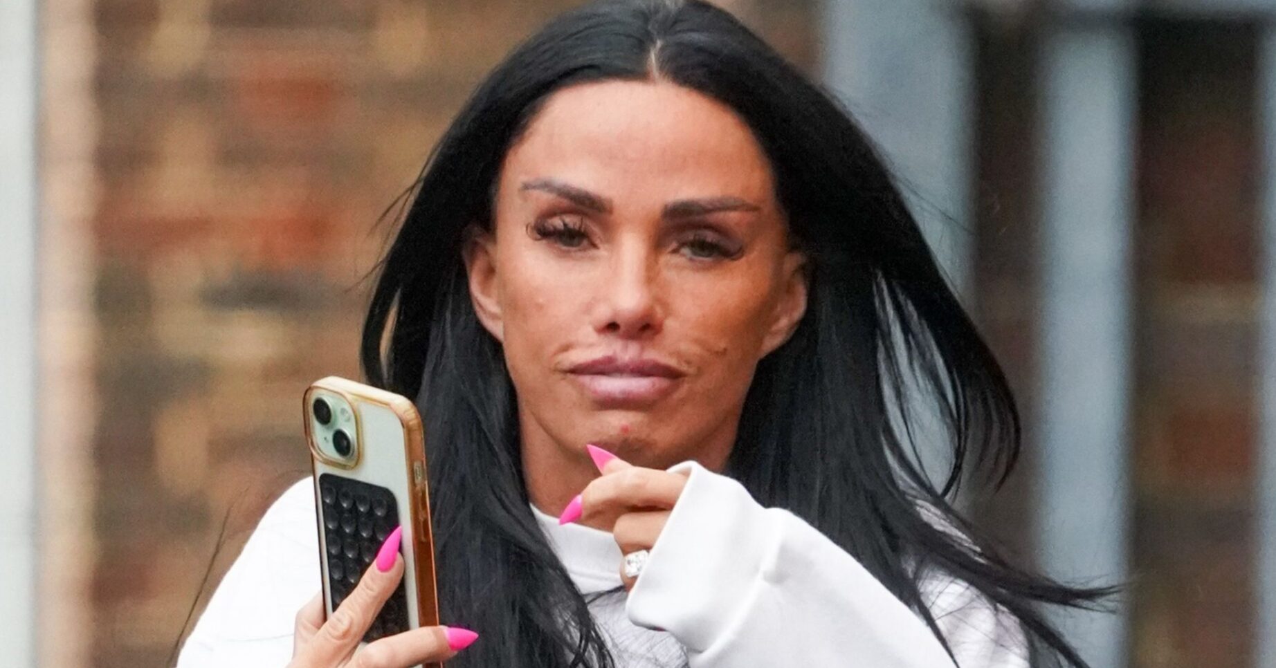 Katie Price frowning holding her phone