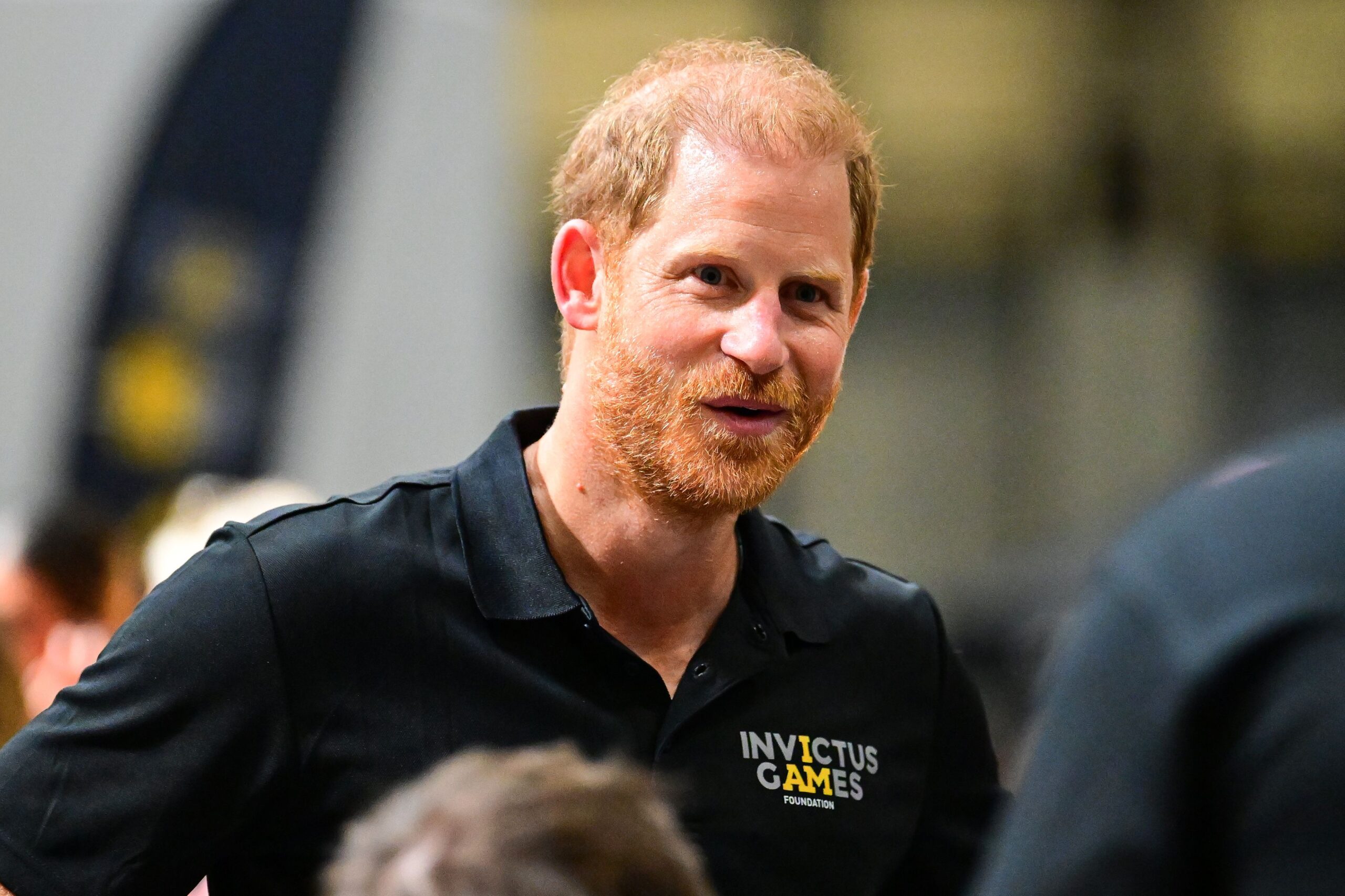 Prince Harry smiling wearing an Invictus Games polo shirt