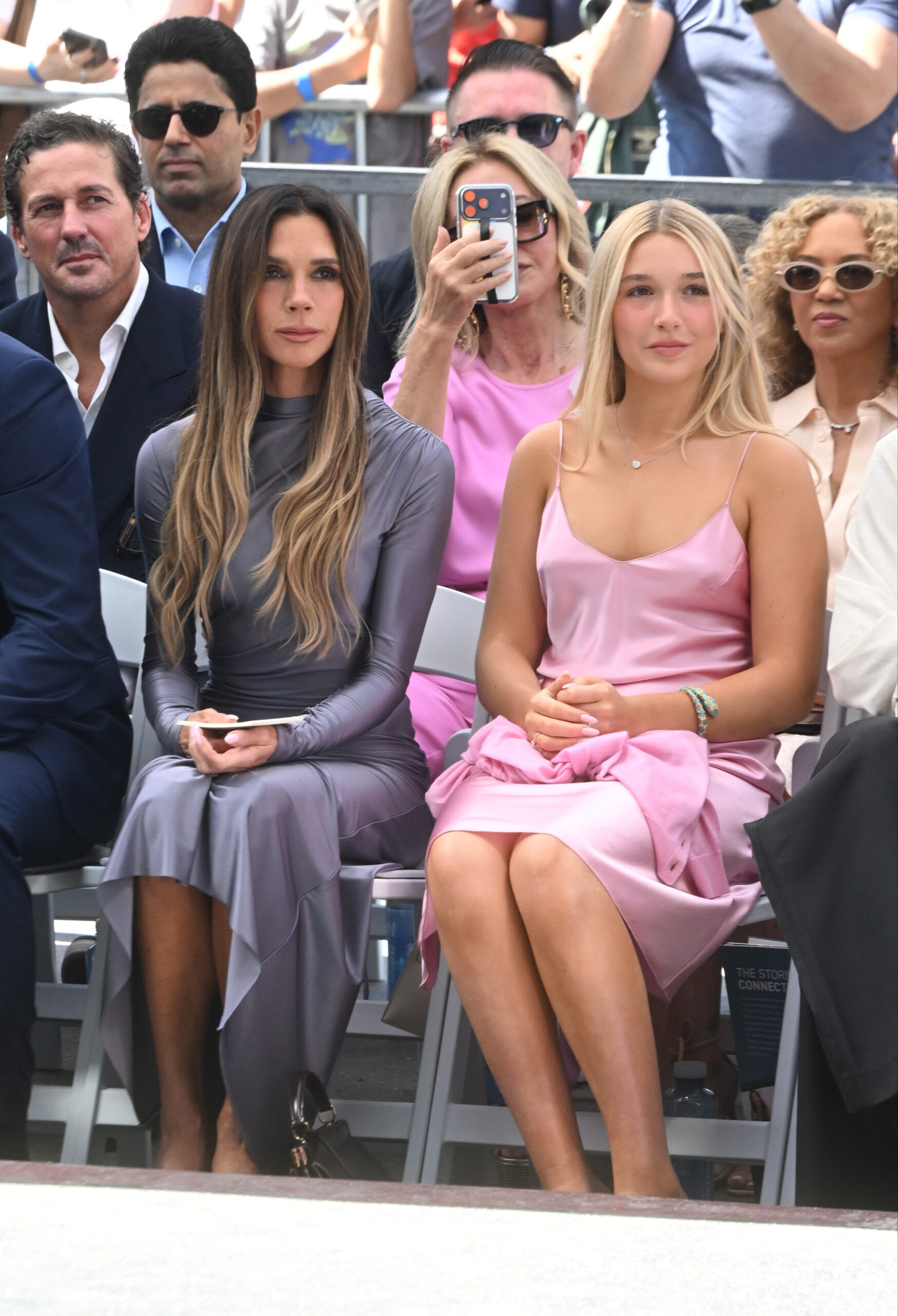 Victoria and Harper Beckham sitting at a show 