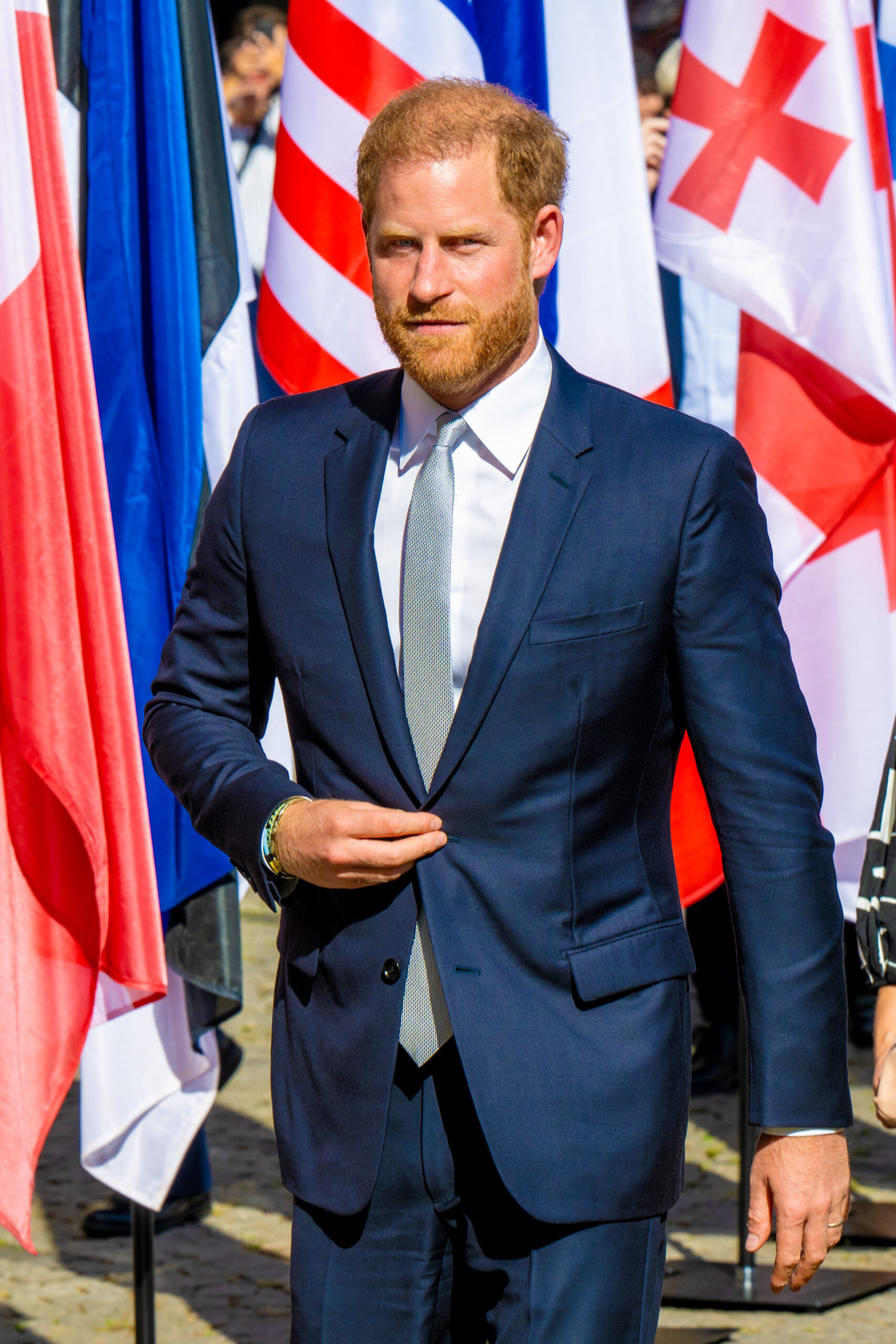 Prince Harry walking in a suit outside 