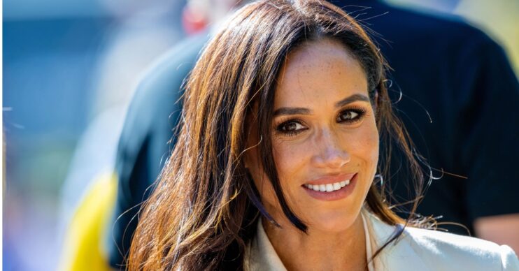 Meghan Markle smiles as she wears white blazer