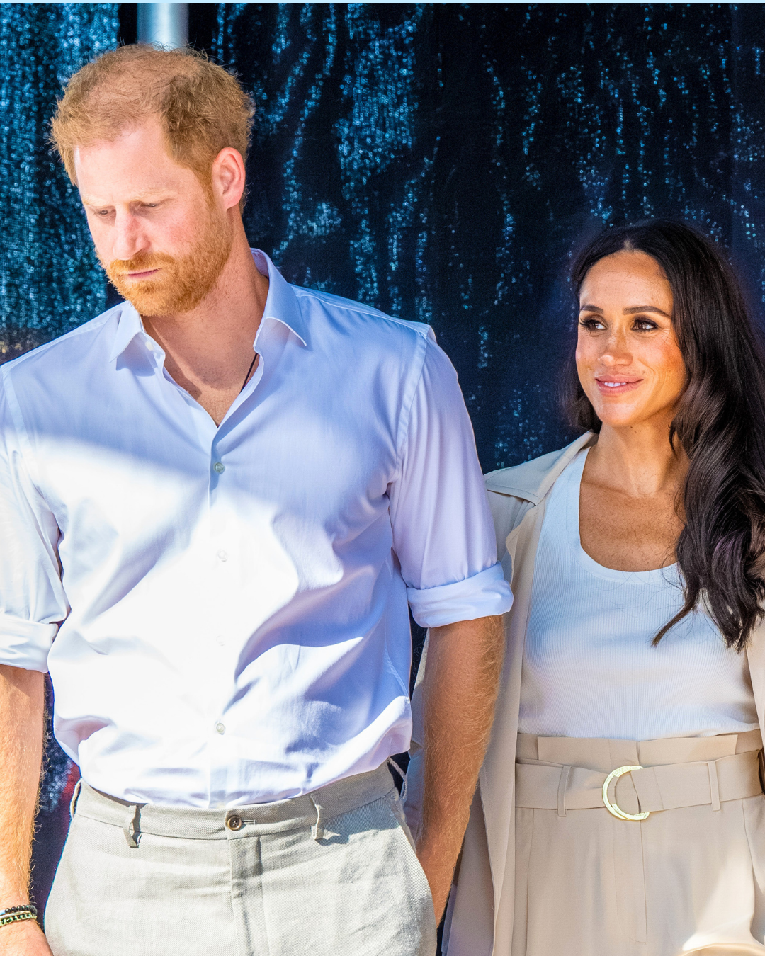 Prince Harry looking down and turning away from Meghan Markle as she smiles