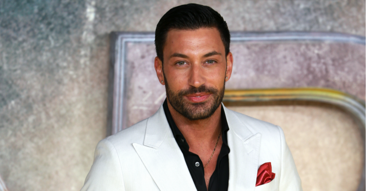 Giovanni Pernice wears a white suit on the red carpet with a black shirt unbuttoned at the top