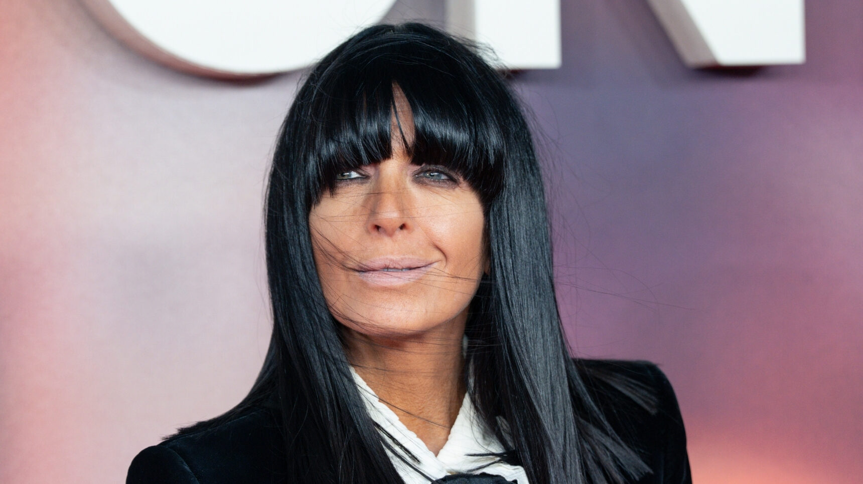 Claudia Winkleman smiling in black suit at event