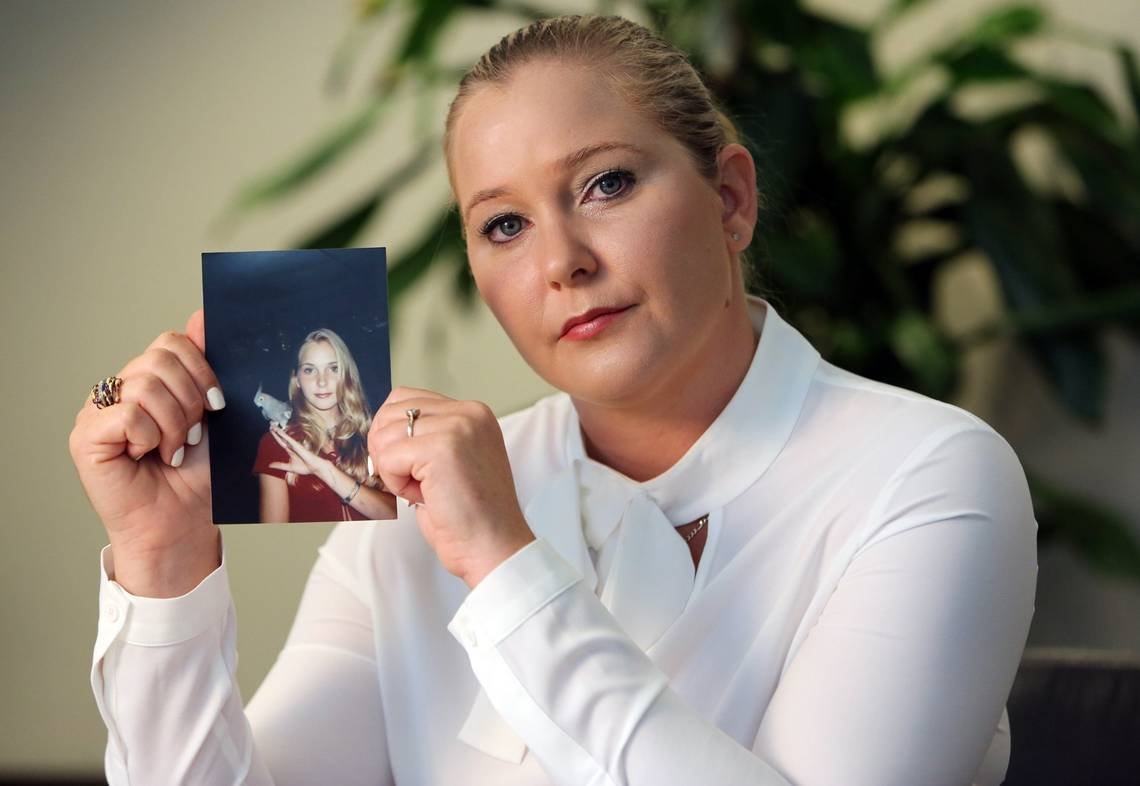 Virginia Giuffre holding up a photo of her younger self