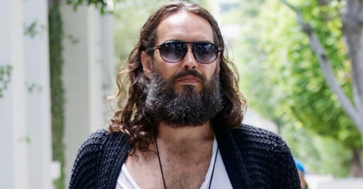 Russell Brand walking in front with sunglasses