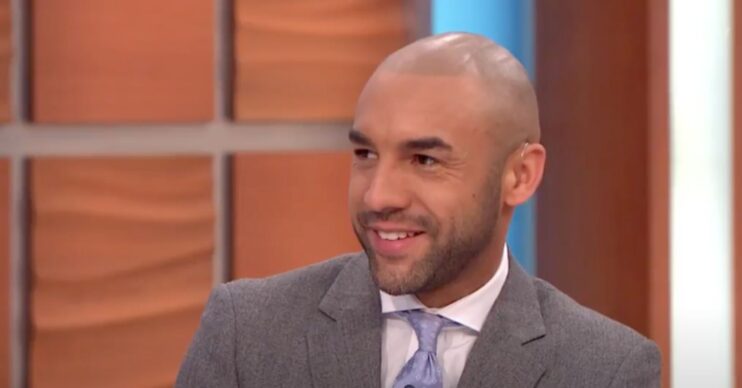 Alex Beresford smiles as he wears a grey suit and periwinkle tie